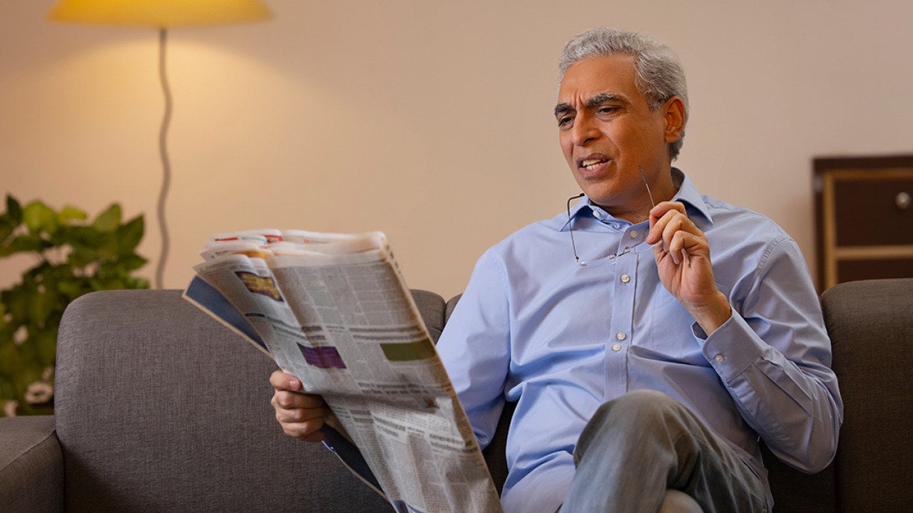 Senior man reading a newspaper in confusion.