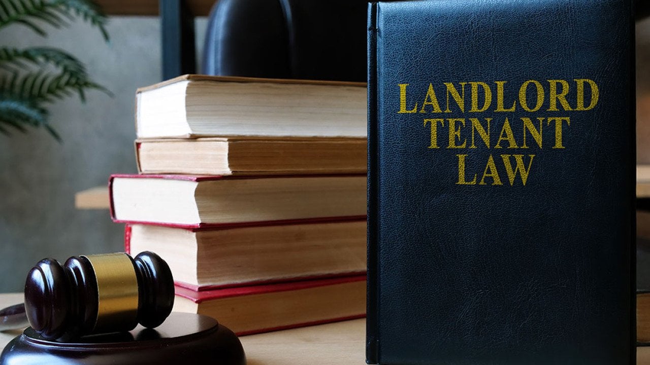 A desk with a judge's gavel on the left, a pile of books with the spines facing away from the camera and a blue book standing upright titled 