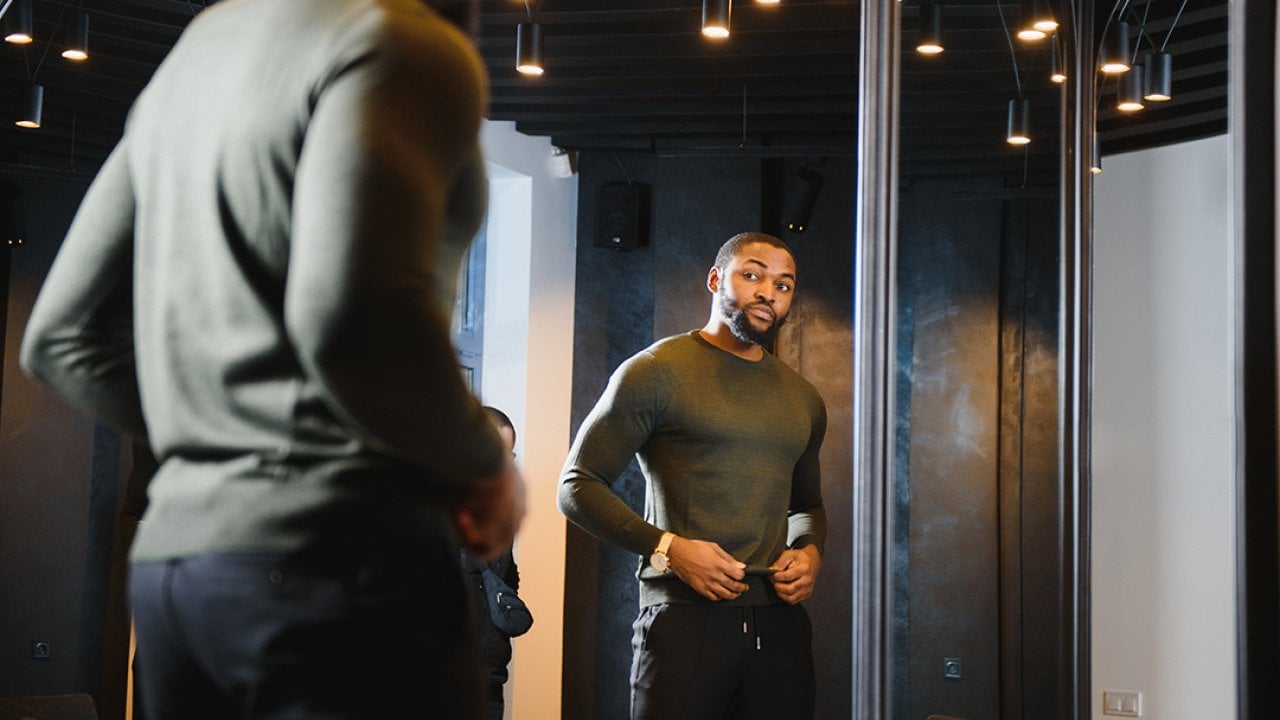 A stylish man looking in front of the mirror to check his outfit.