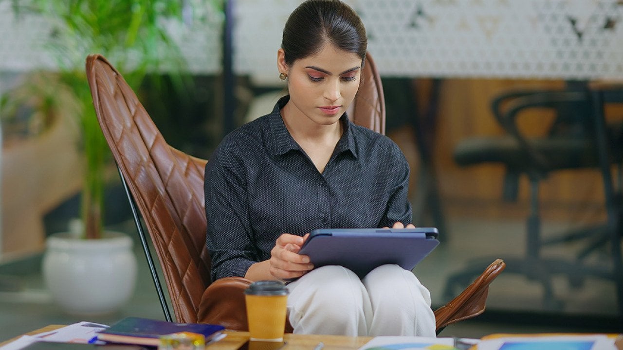 Young businesswoman in workplace using a tablet to browse information online.