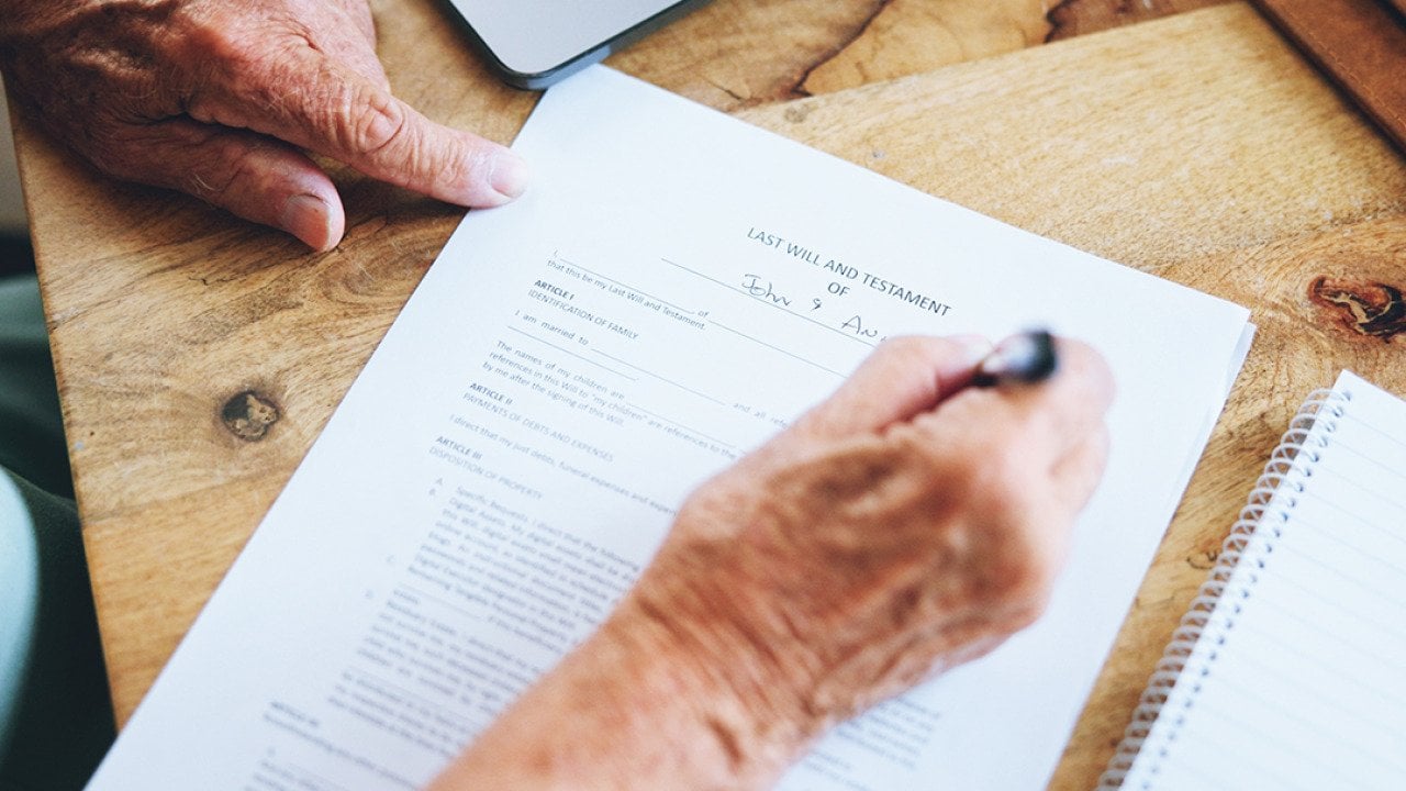 A senior person signing a last will and testament document.