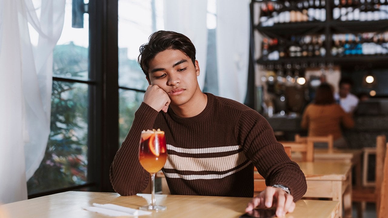 Young man who was ghosted by his date sits alone disappointed in a restaurant.
