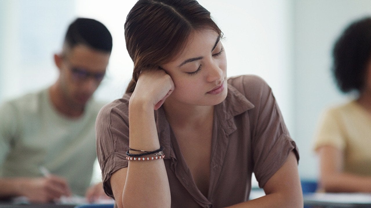 Young female college student feeling burned out in a classroom.