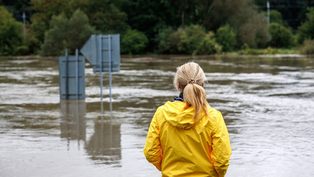 A woman in a raincoat looking over a huge flood.