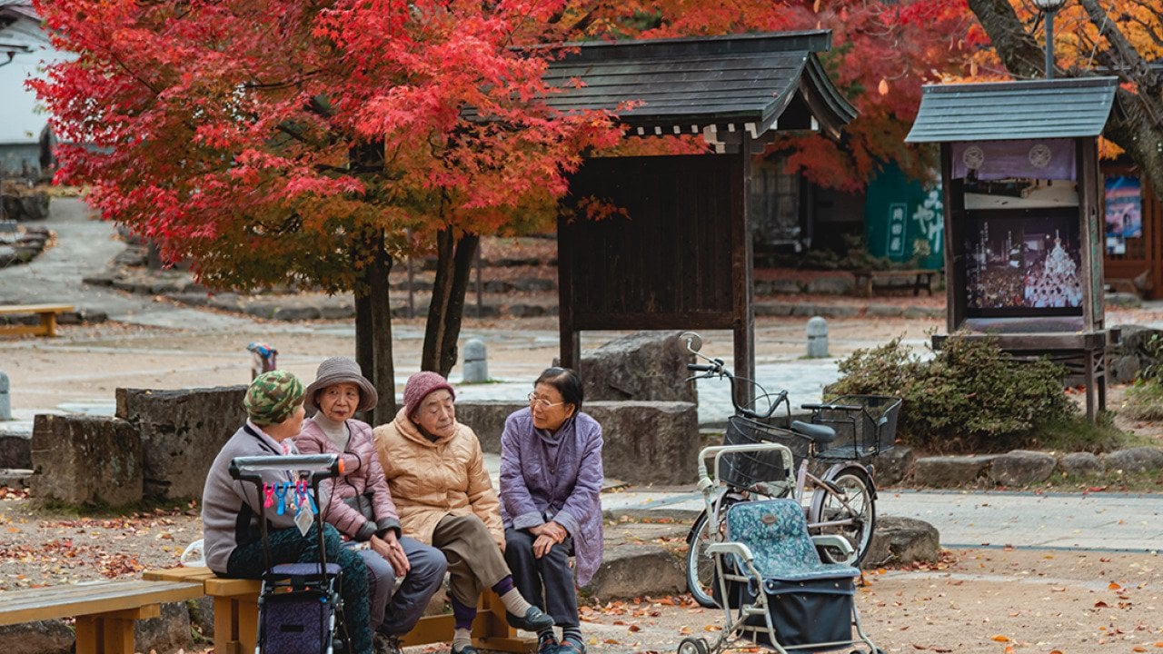 Four elderly women chatting in a garden in Takayama, Japan.