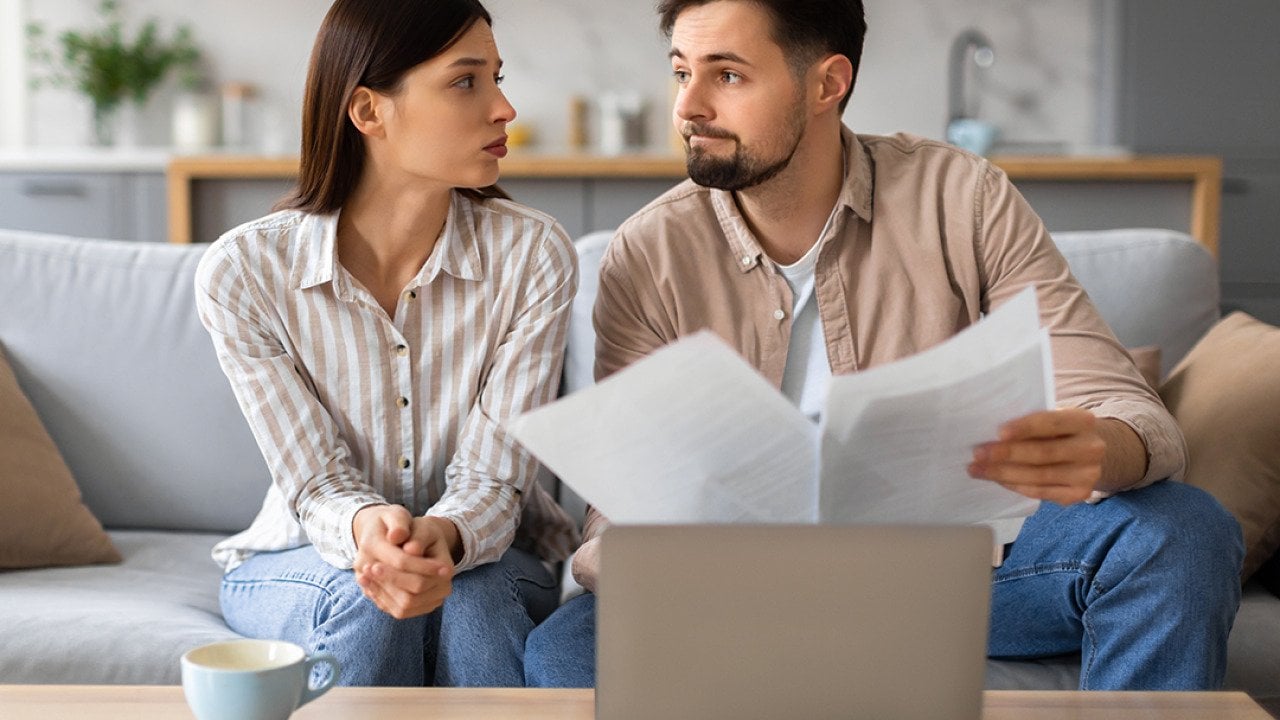 Young couple looking at each other with a serious expression while going through financial documents.