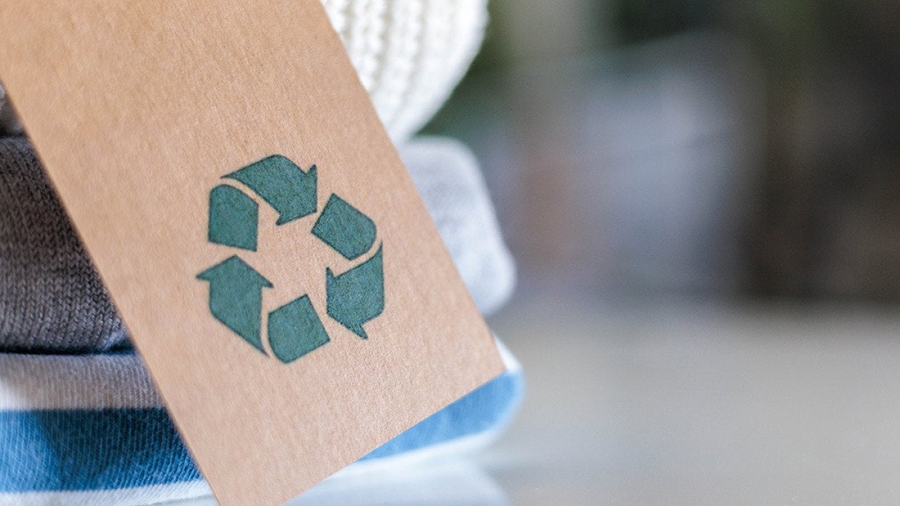 Knitted clothes with a craft tag showing the recycling symbol.