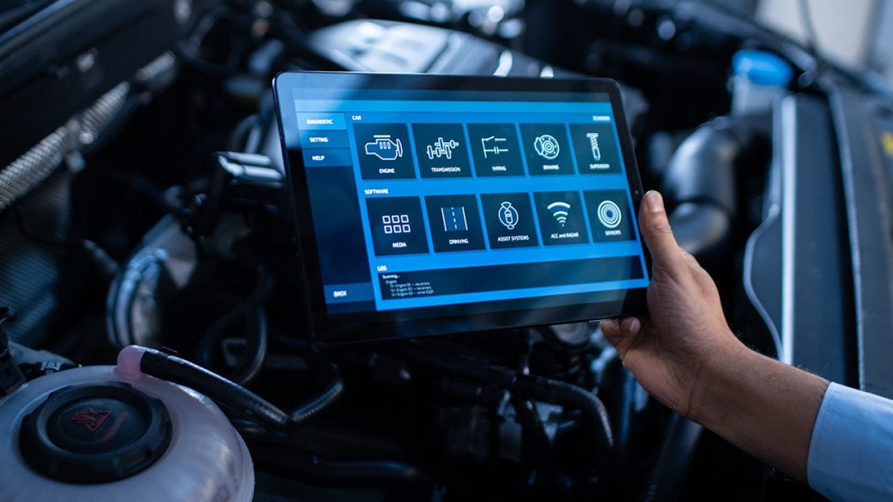 A mechanic using a tablet to configure a car's issue and repair.