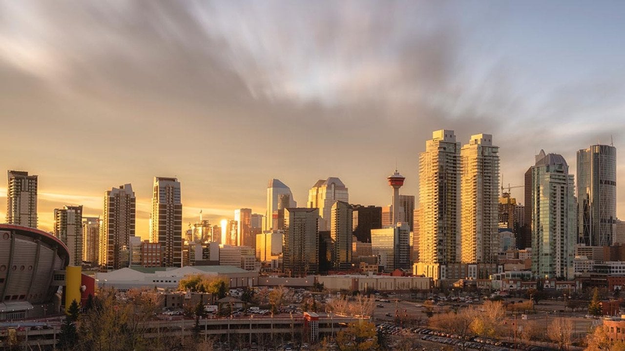 Skyline of Calgary during sunset with golden light reflecting off skyscrapers.