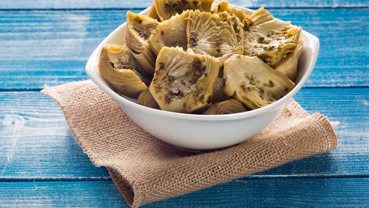 A bowl of grilled artichokes in oil.