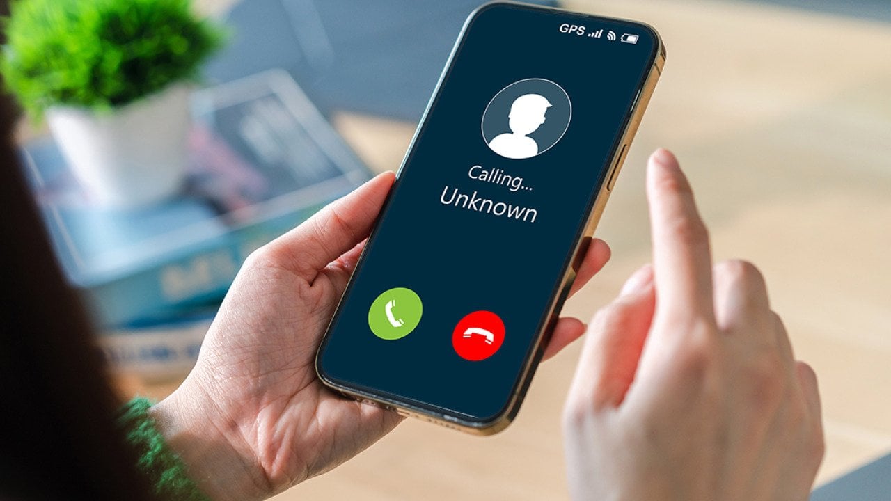 Woman contemplating to answer an unknown call on her mobile phone.