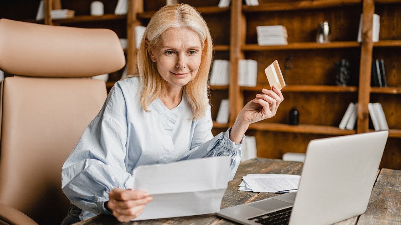 Senior businesswoman using company card to pay a bill online.