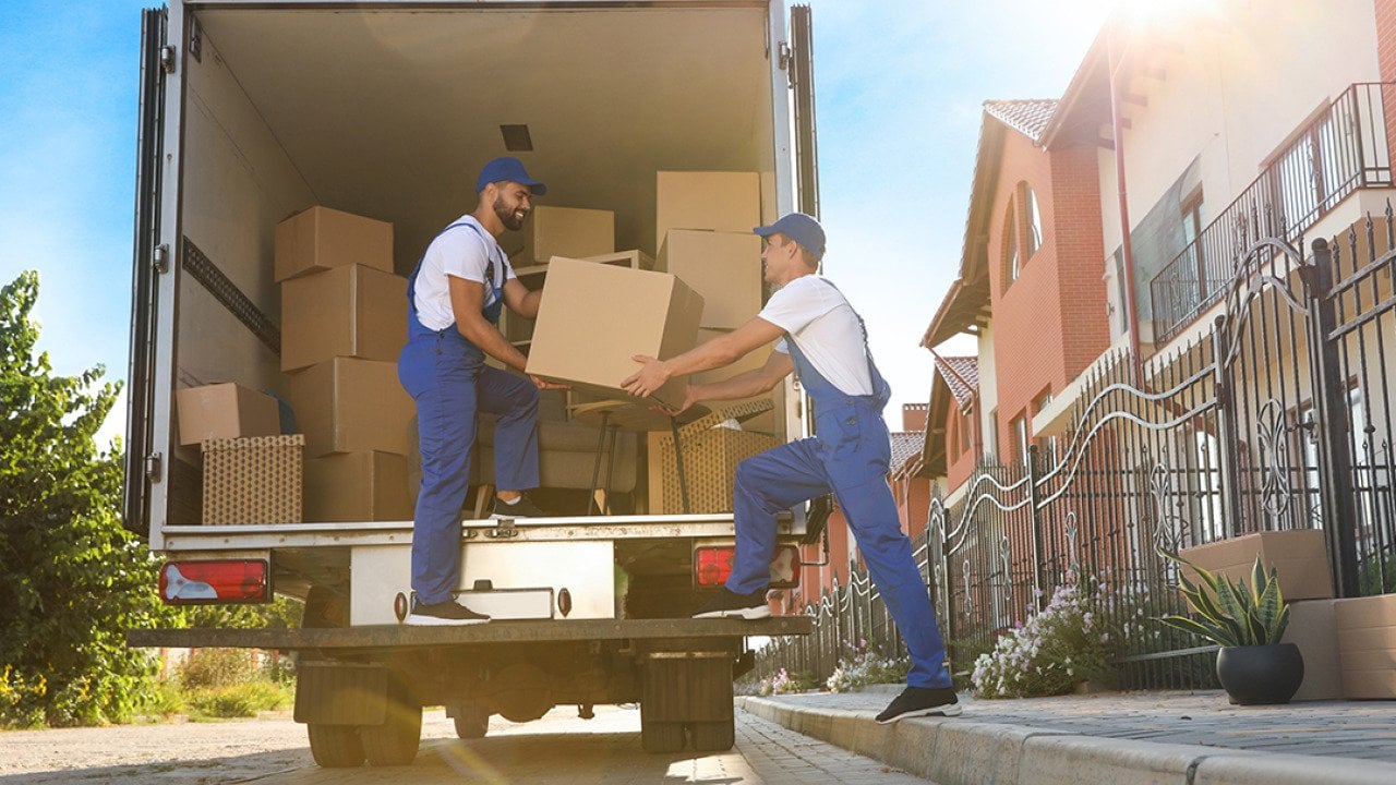 Two workers unloading boxes from a truck servicing a relocation.
