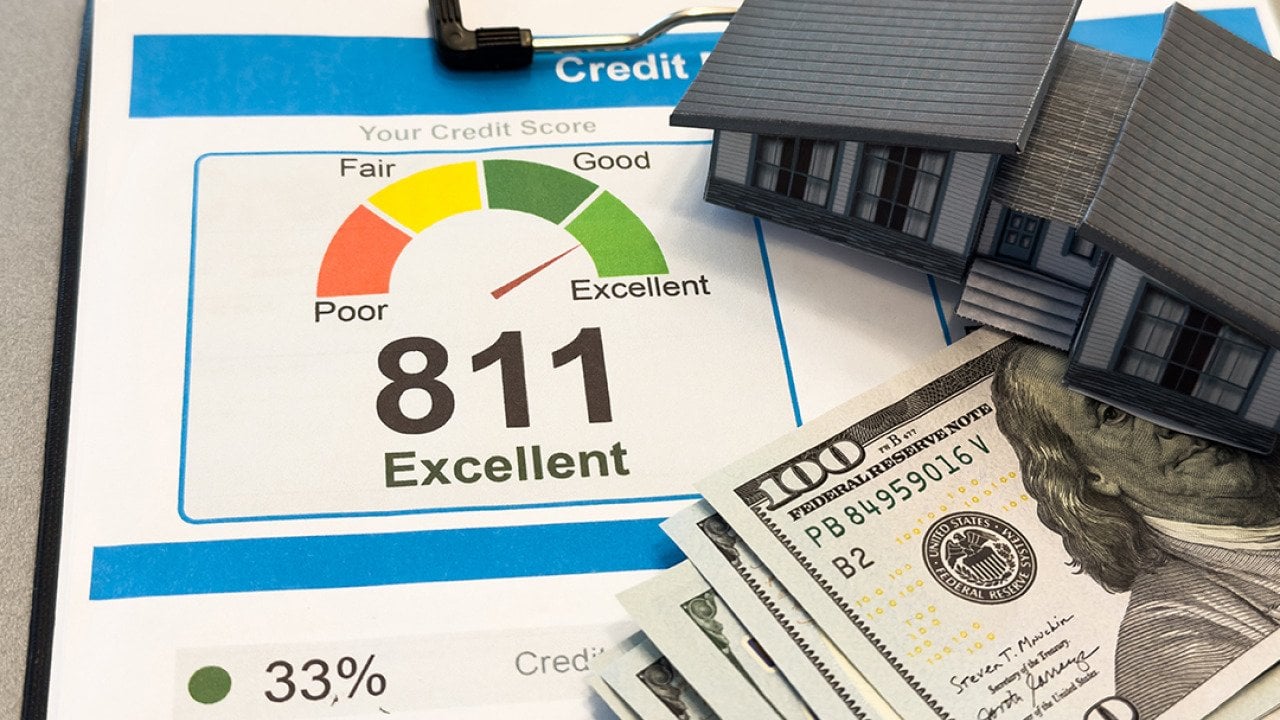 Figure of a house made of paper with credit report letters and cash around it.
