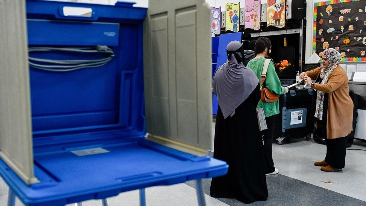 An election official assists voters ready to turn in their ballots for the US presidential and congressional elections at Dearborn High School in Dearborn, MI, United States on November 05, 2024.