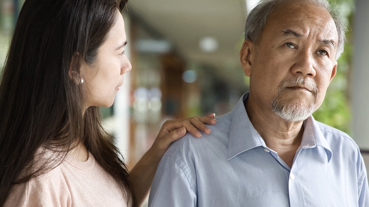 A middle-aged daughter looking worried at his elderly father who has dementia.