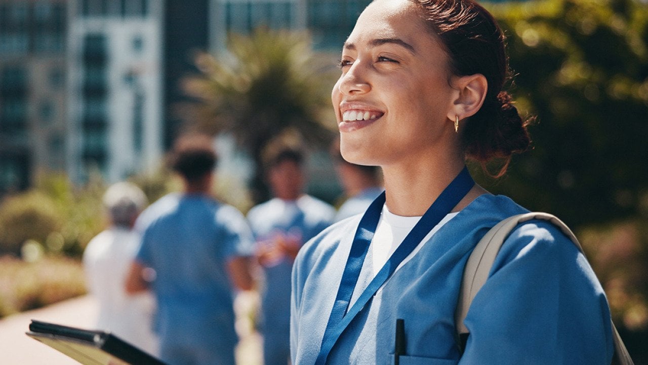 A nursing student happily using a tablet inside campus.
