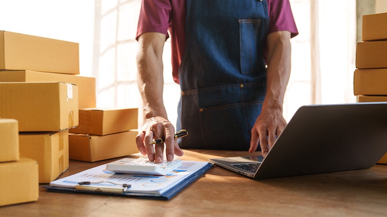 Small business owner calculating orders.