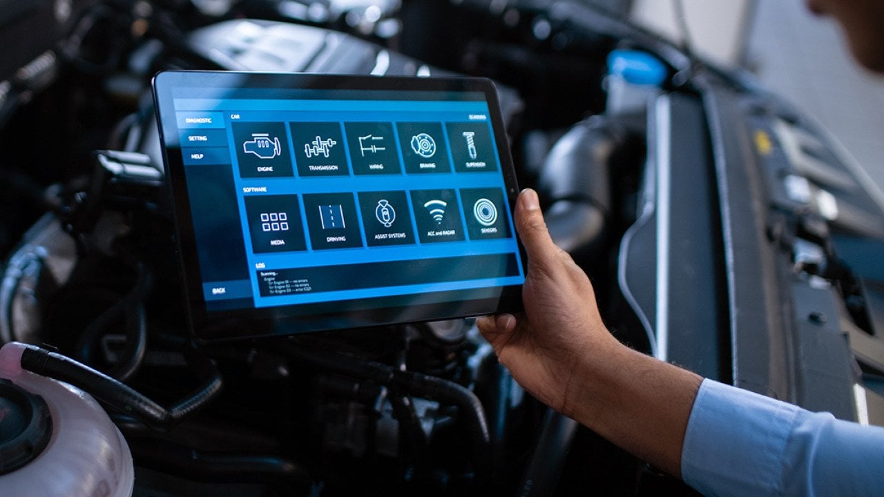 Car mechanic using a tablet to diagnose a car's components' issues.