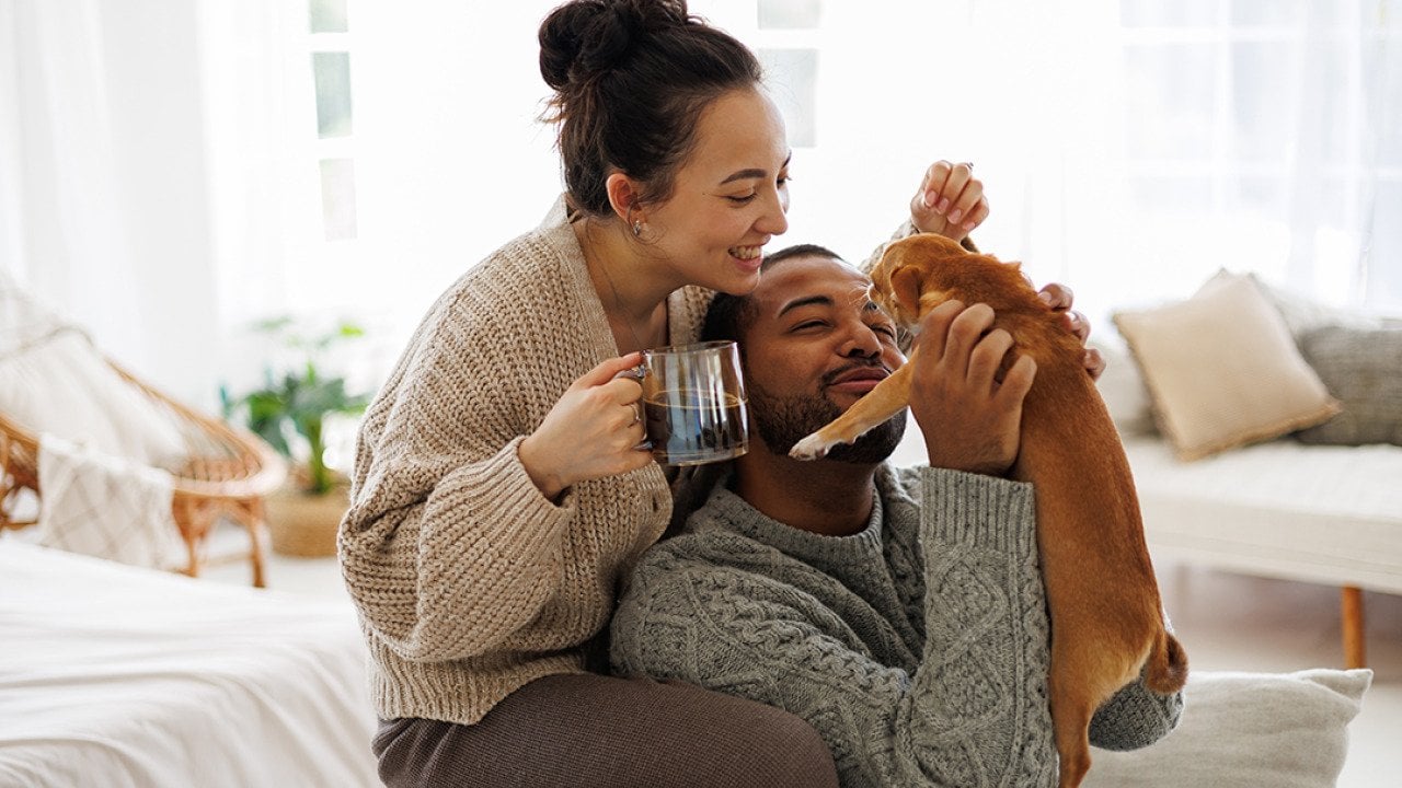 Happy couple at home playing with their dog.