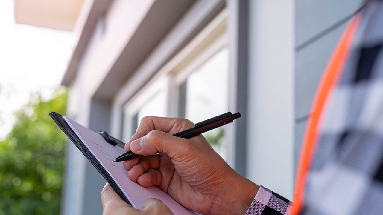 An inspector checking off a list while looking at a property.
