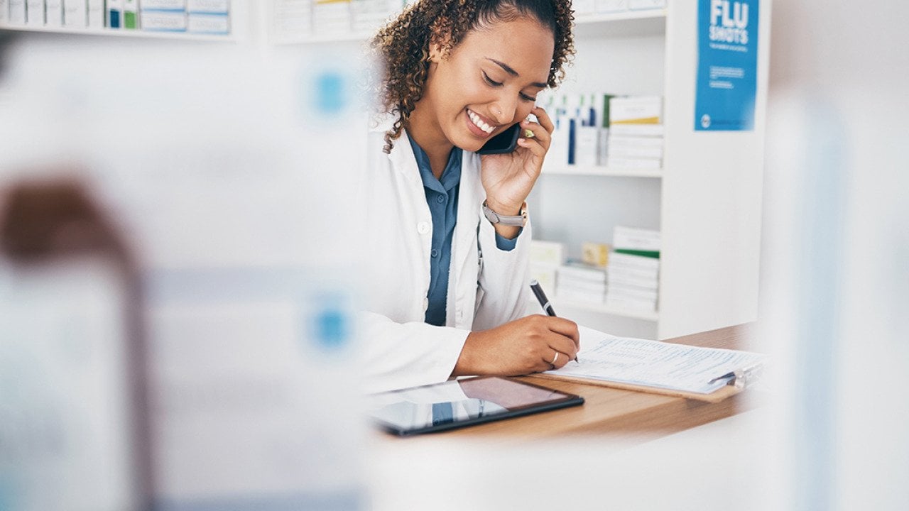 A pharmacist taking a call and listing a customer's order.