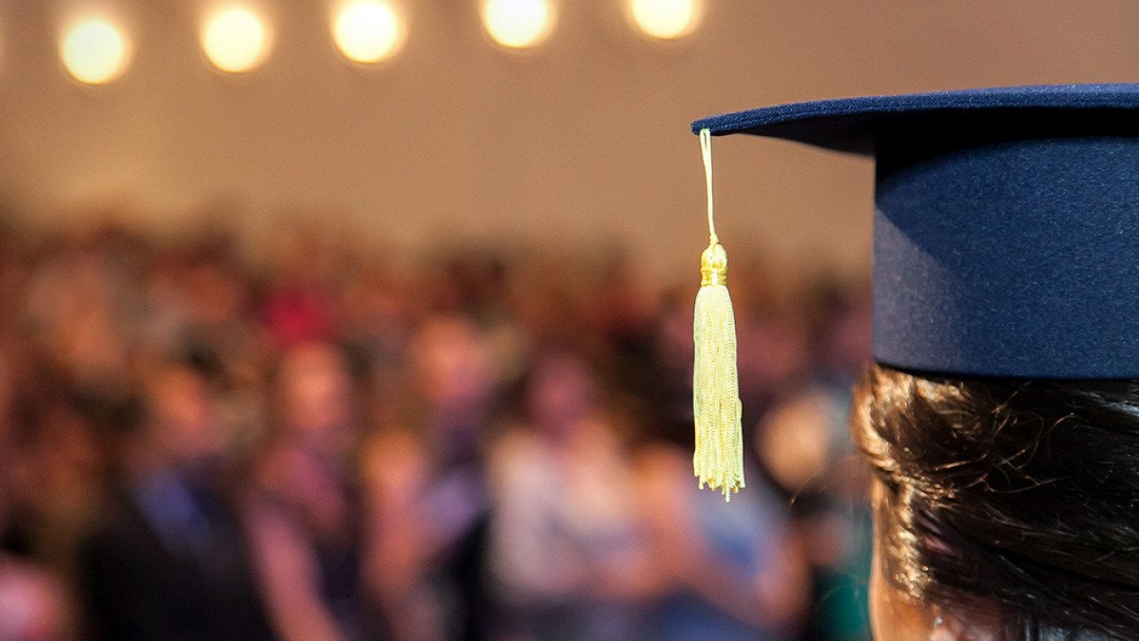 A graduating student facing the ceremony crowd.