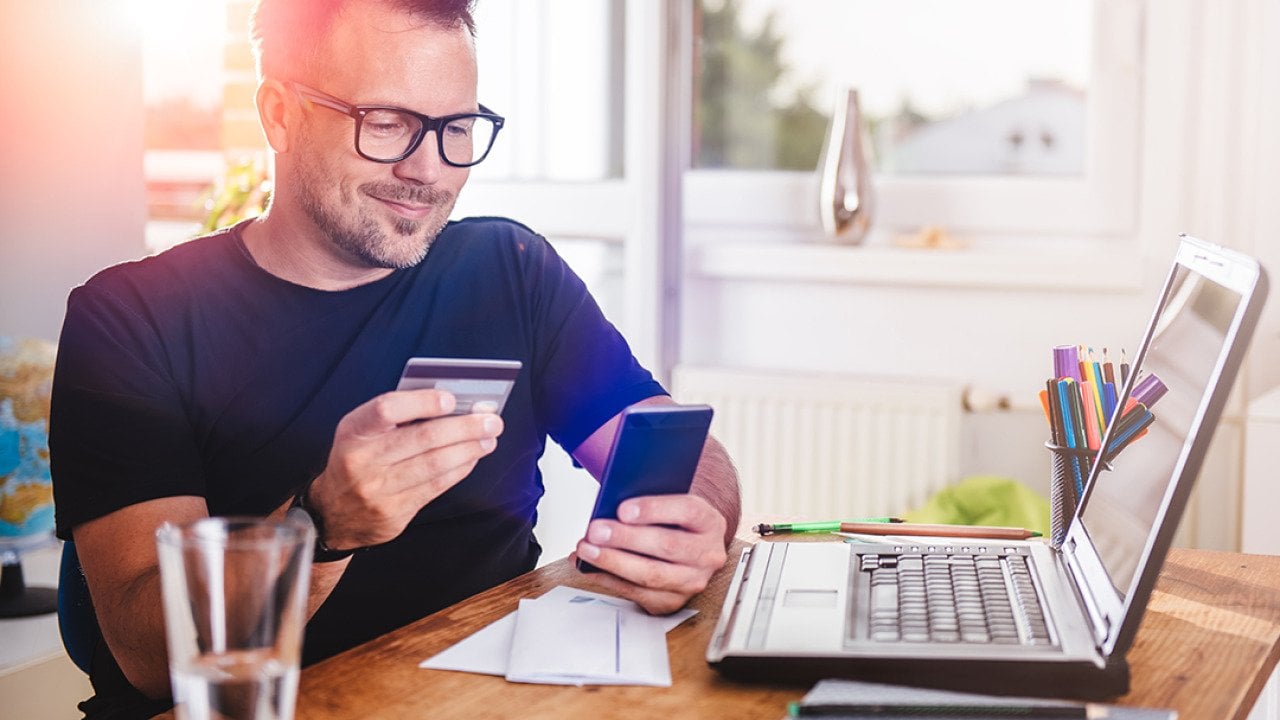 Man in his home office using a credit card for an online transaction.