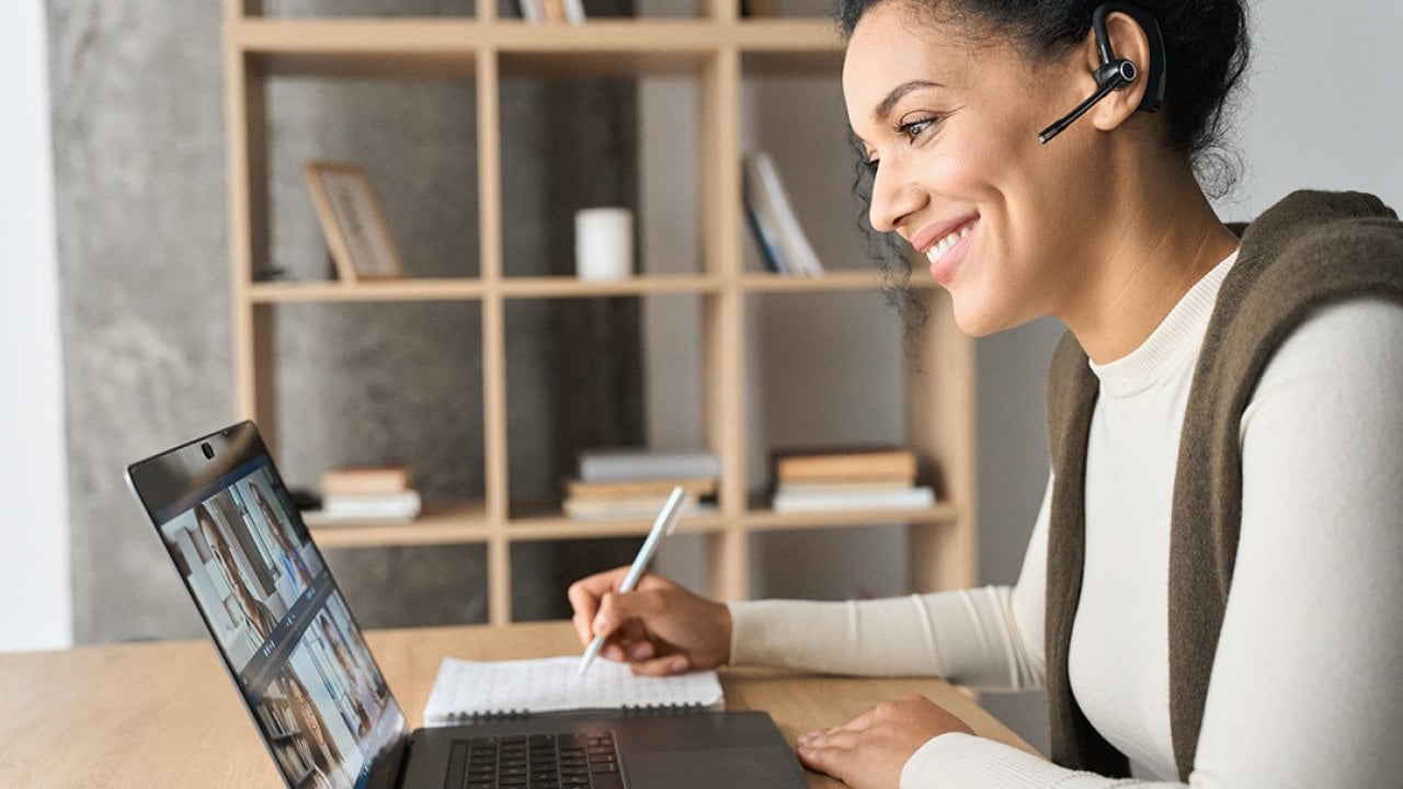 Young female professional engaged in a virtual meeting while working from home.