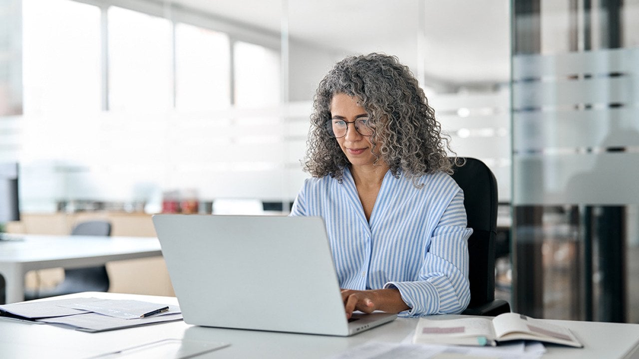 Middle-aged businesswoman busy working on tasks in her laptop in an office.