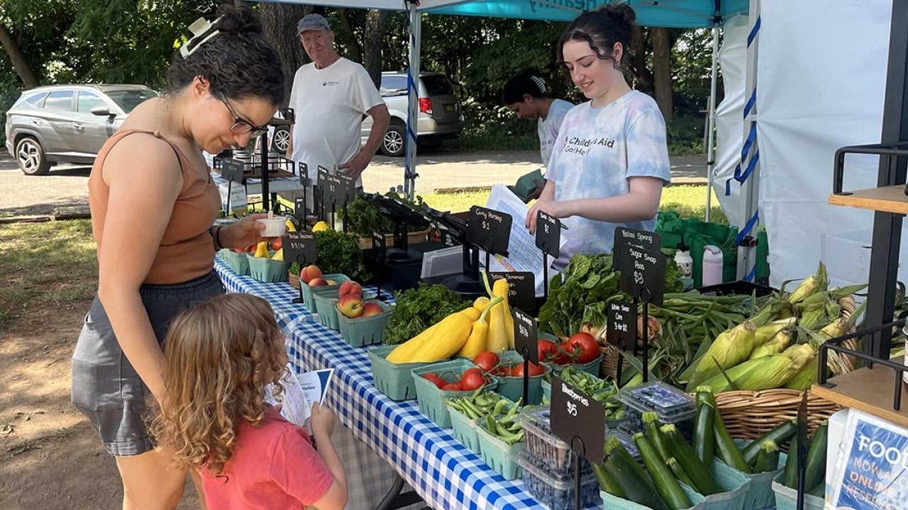 Ana Garcia, 41, and her 3-year-old son, Elliott, pick up a Food Box at a table full of colorful produce at the Goodhue Community Center on Staten Island 