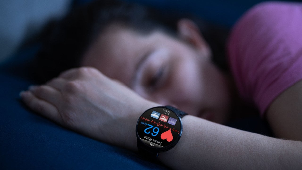 Person wearing sleep tracking heart rate monitor smartwatch in bed.