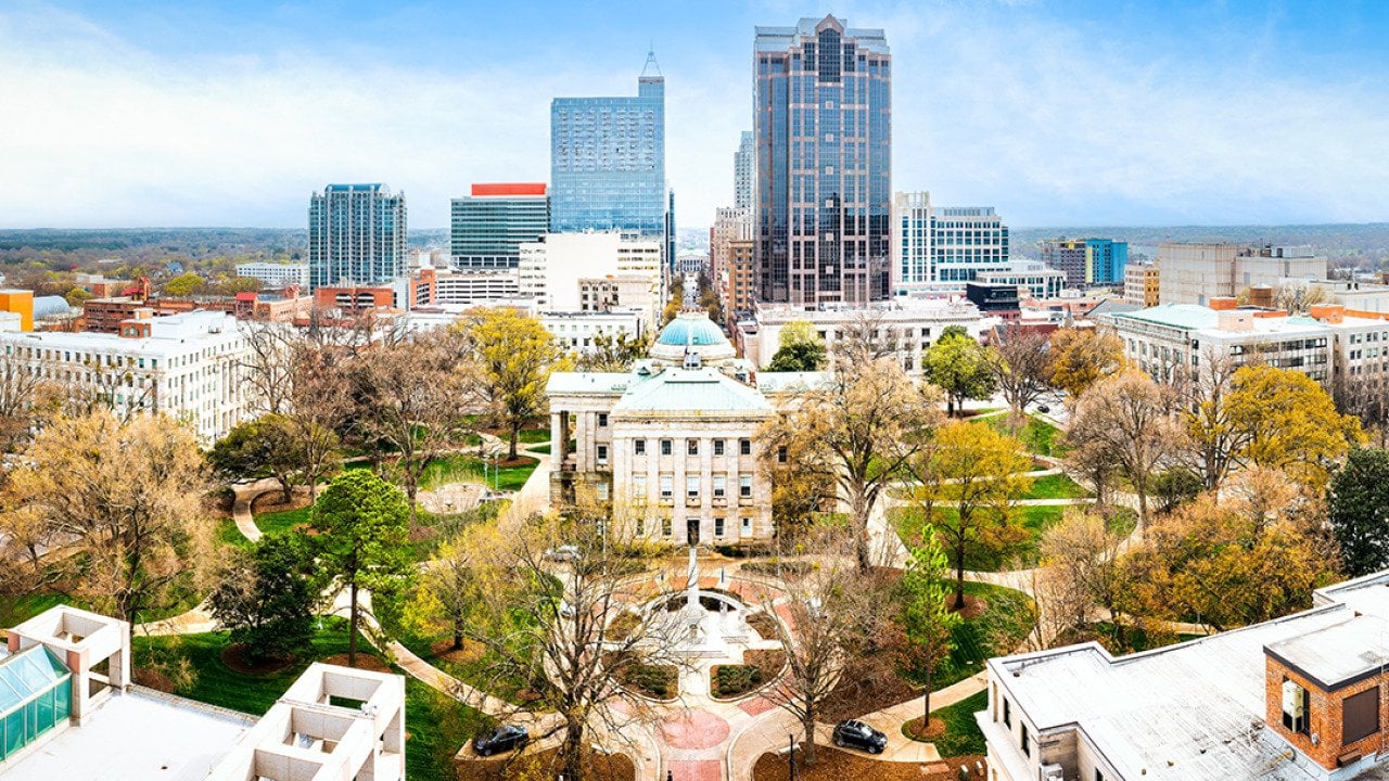 Aerial view of the North Carolina State Capitol and Raleigh skyline.