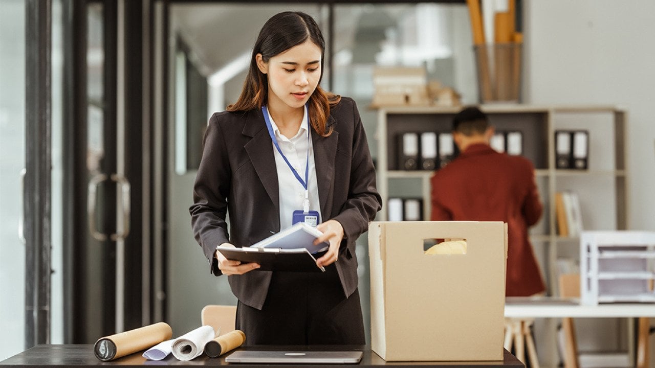 Young businesswoman preparing her work items to put in a box after being laid off.