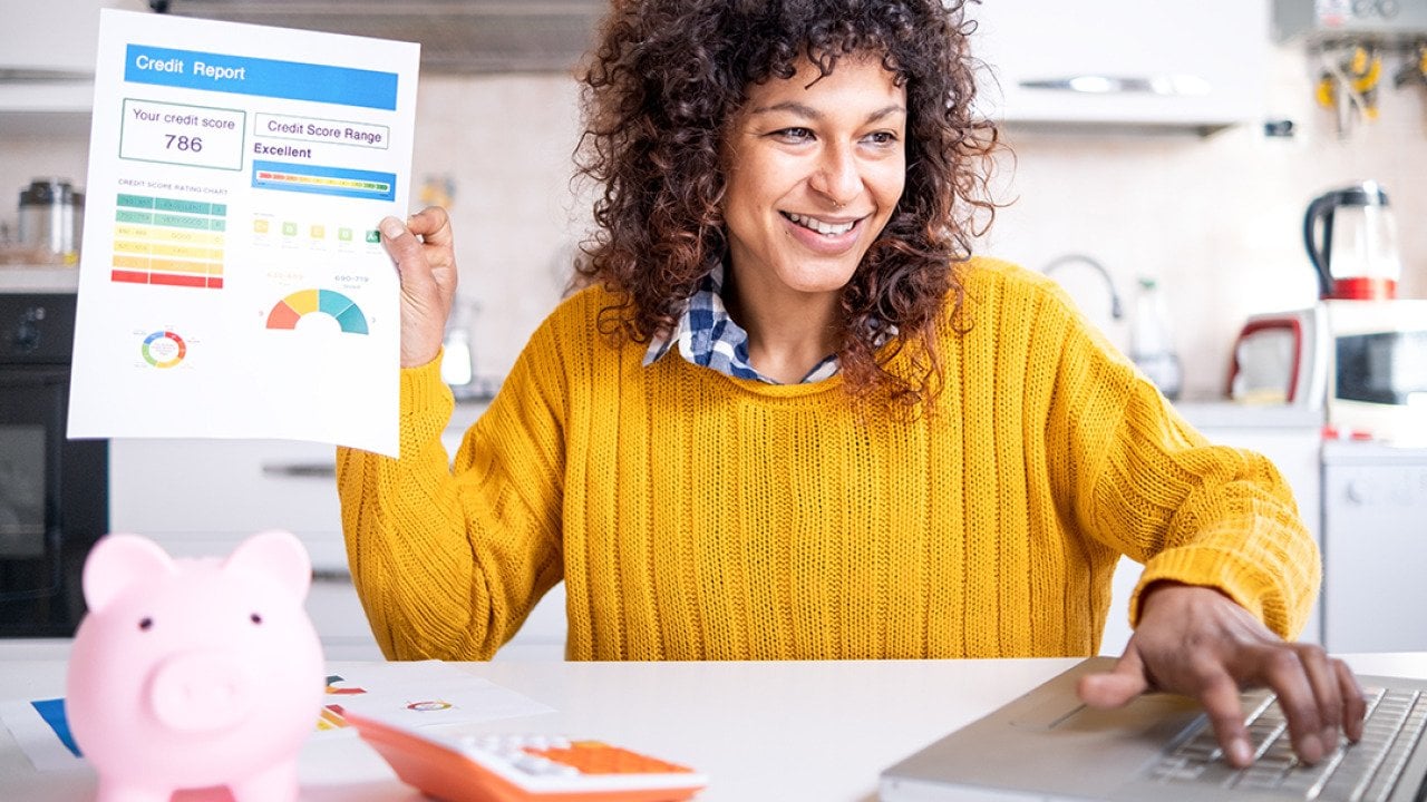 A woman happily holding up a good credit score report.