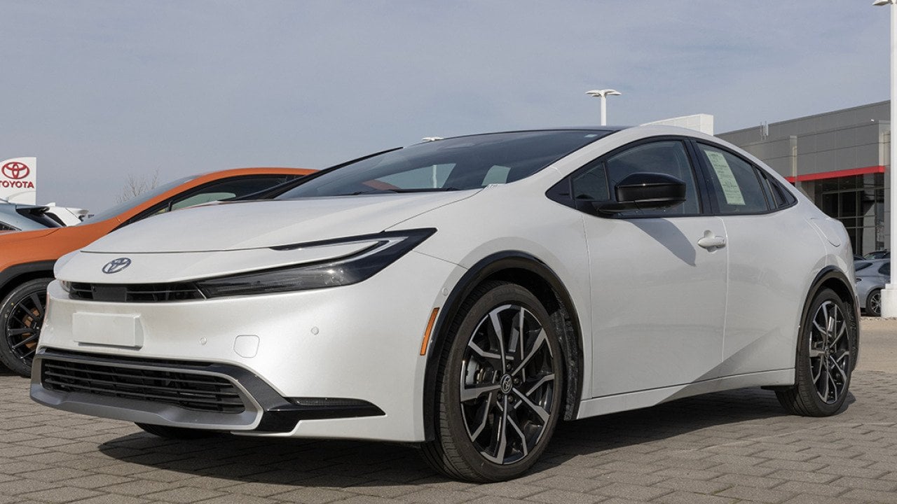 A used white Toyota Prius on display at a dealership.