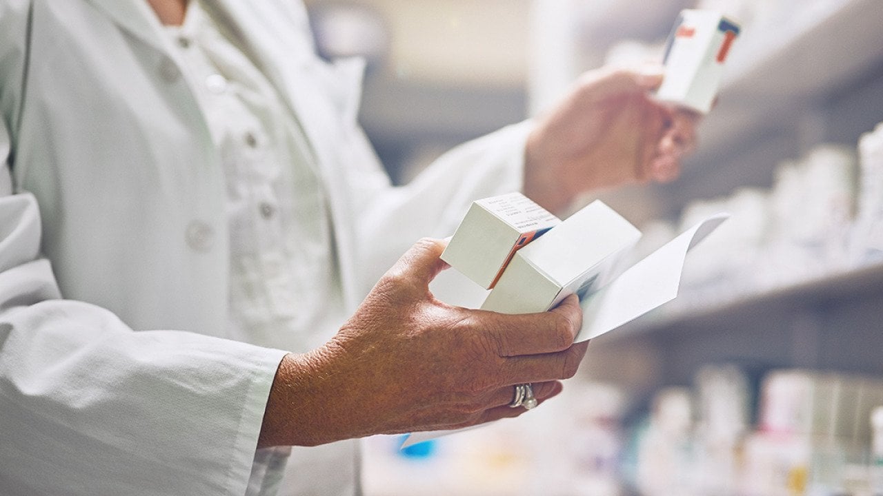 Pharmacist looking at multiple boxes of drugs.