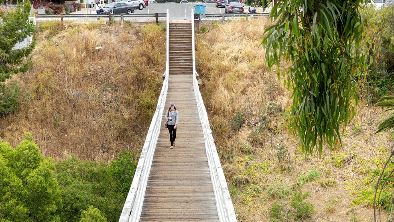 A woman walking across the Quince Street Bridge in Banker's Hills in San Diego, California.