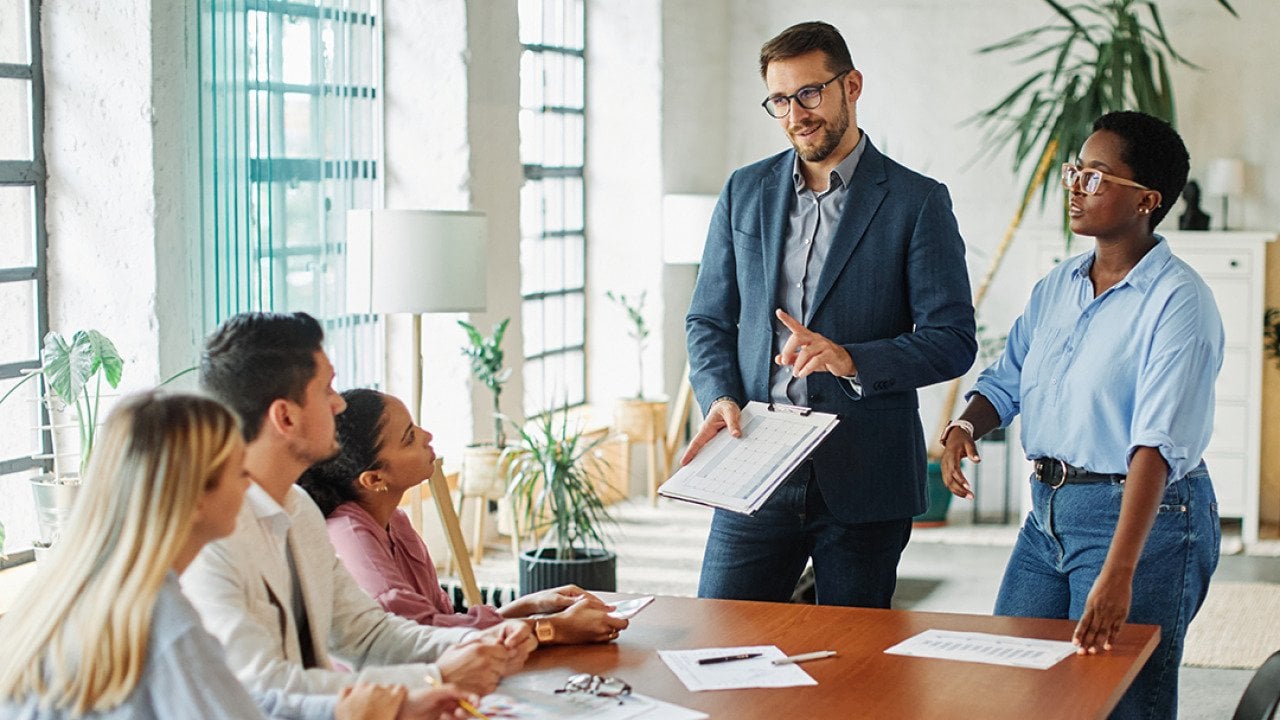 Five members of a diverse business team in a meeting in an office.