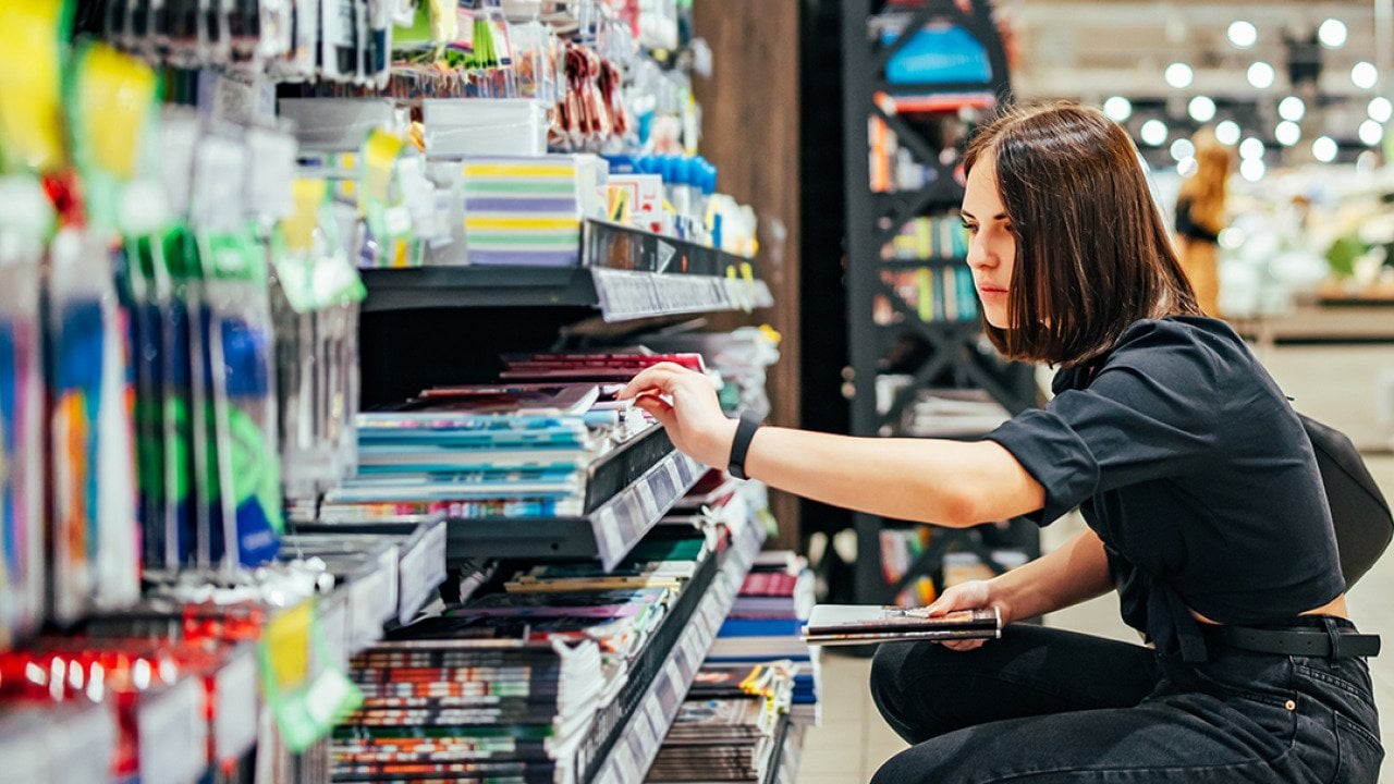 A young woman choosing school supplies at a supermarket.