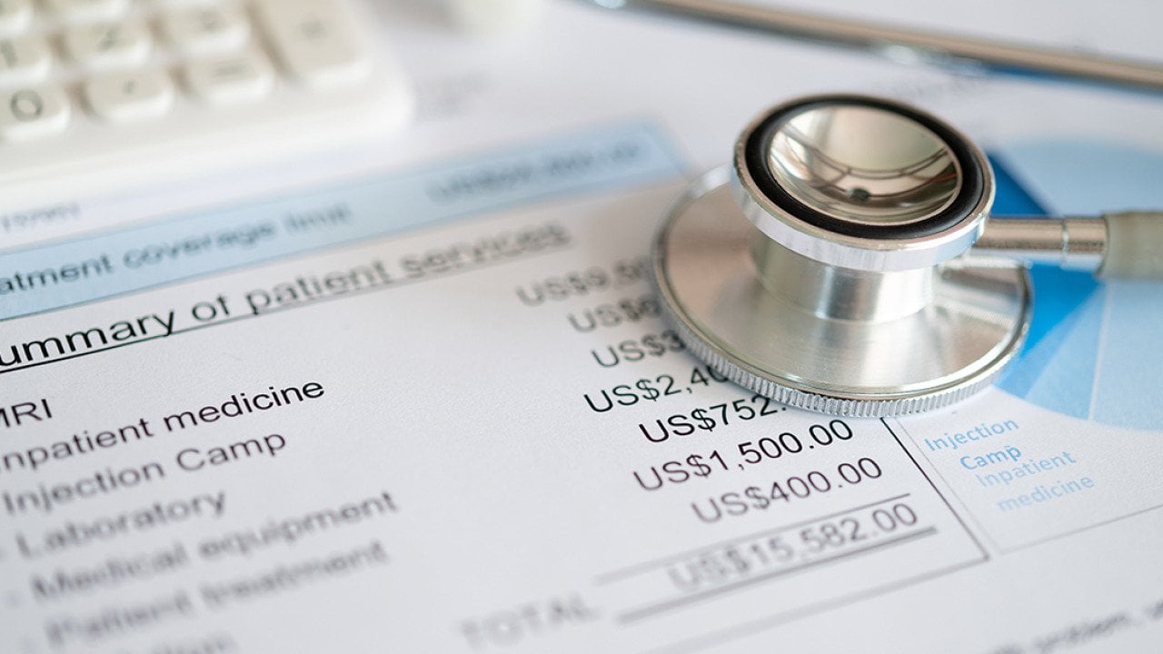 Stethoscope on top of medical expenses bill.