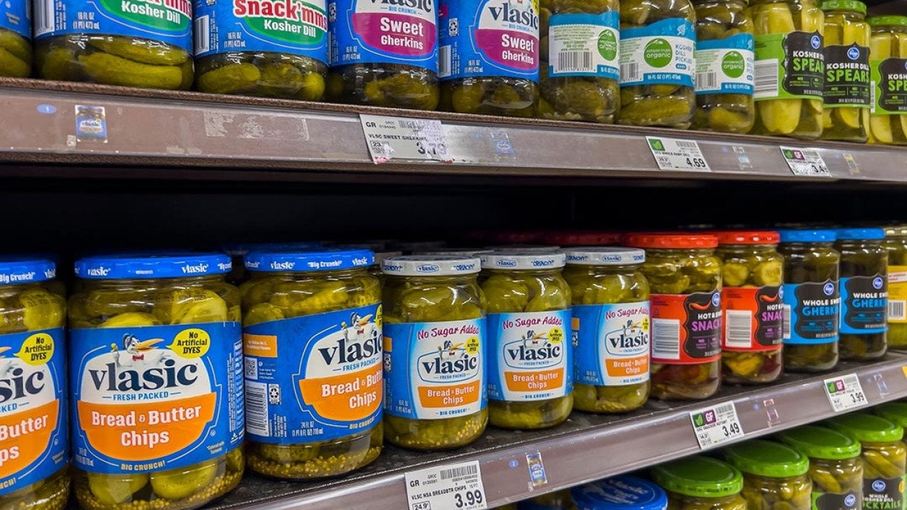  Close up of three shelves of jars of pickles starting with vlasic brand for sale in a grocery store. 