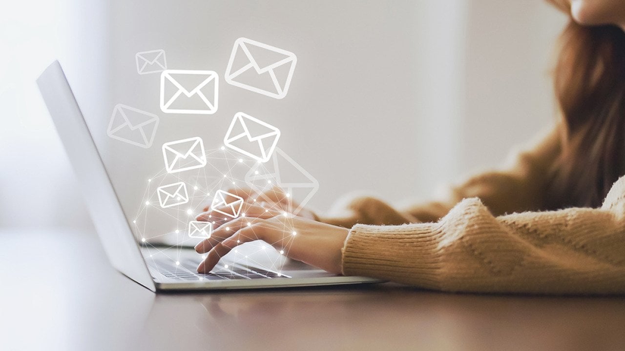 A marketing professional working on her laptop illustrated with graphics of email and newsletter.