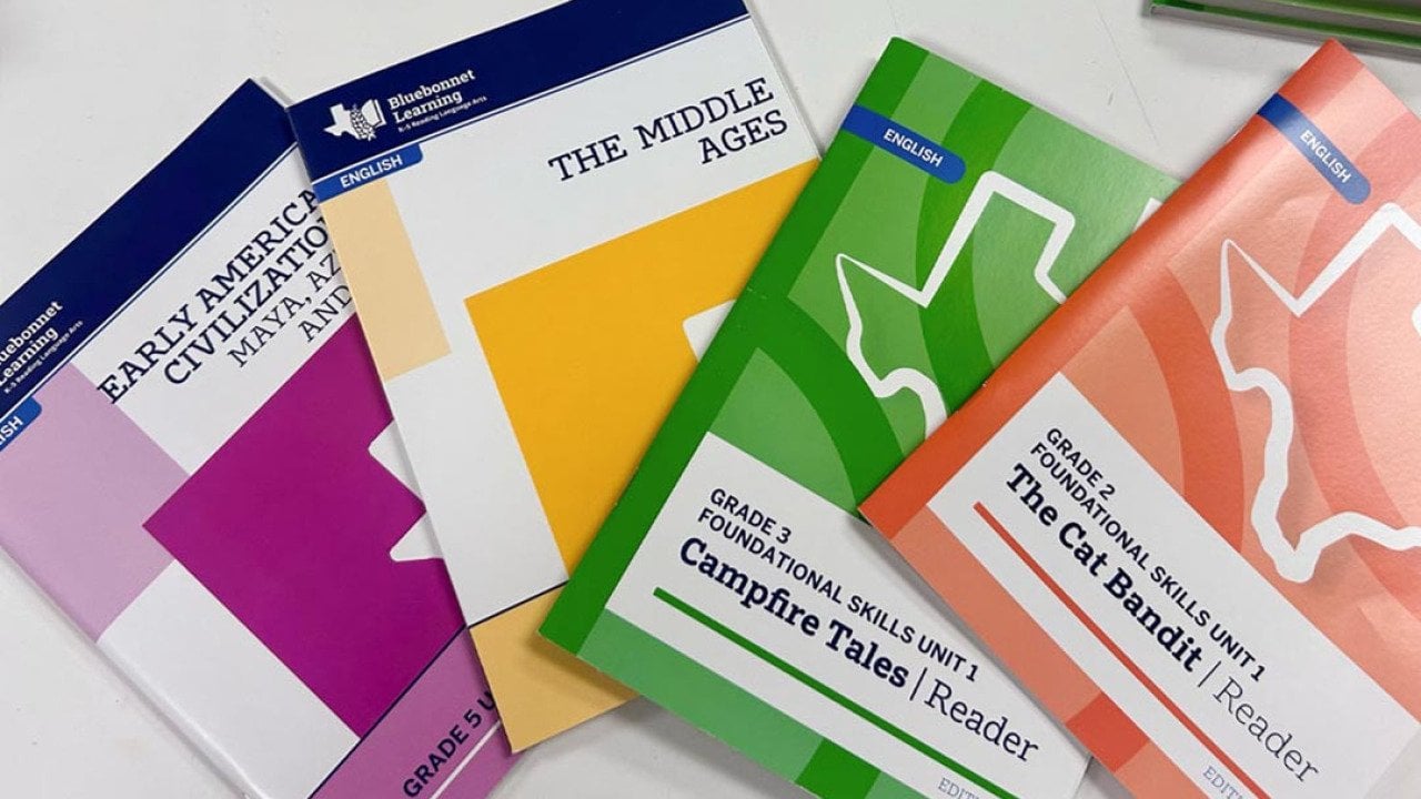 Four Bluebonnet readers in different colors, the new K-5 Texas reading curriculum that includes multiple biblical references.    