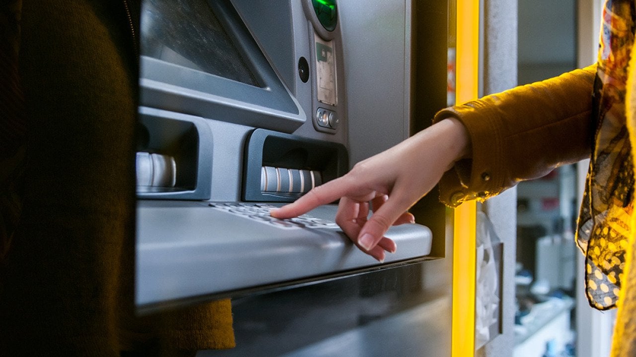 A woman entering info in an ATM to withdraw money.