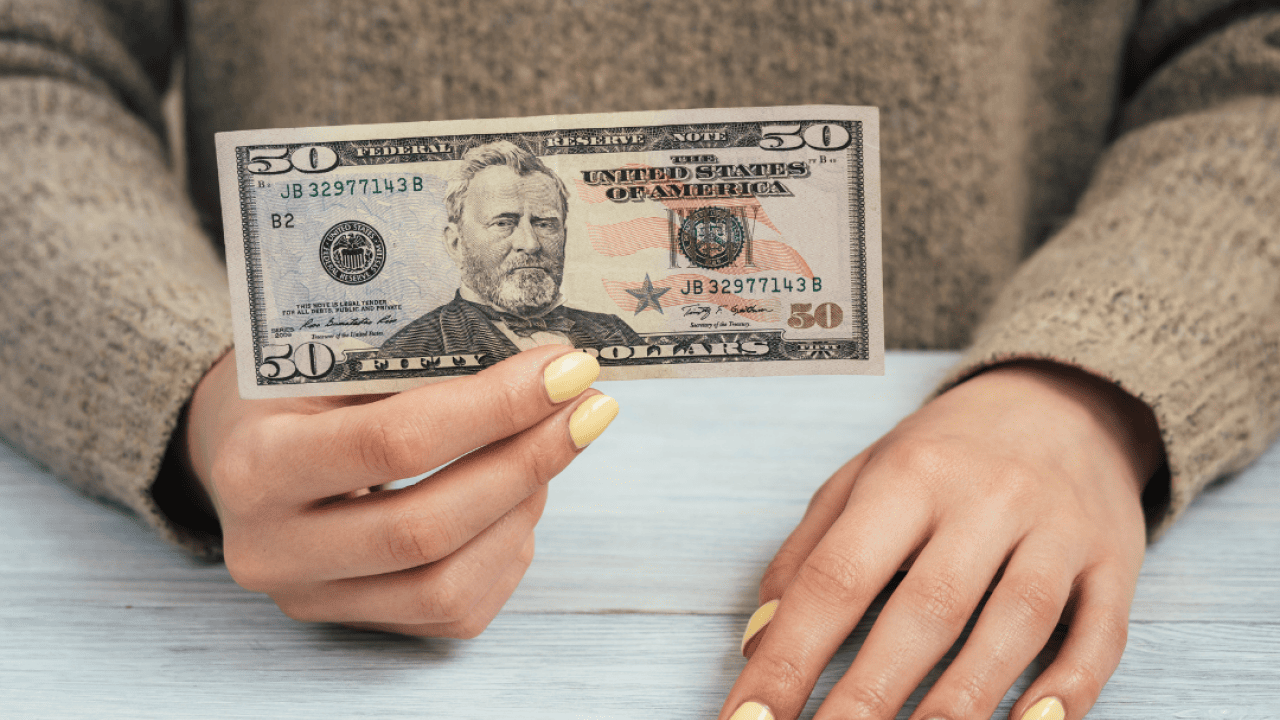 A woman holding a $50 banknote.