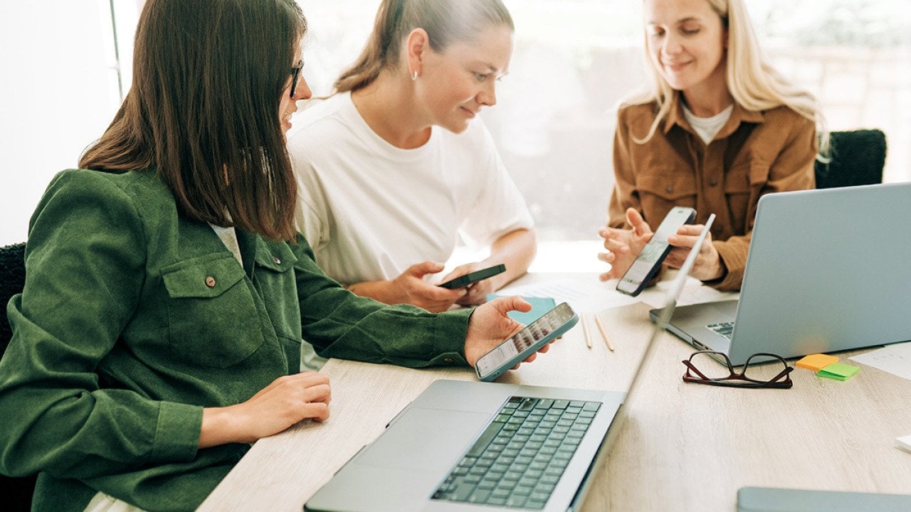 Three businesswomen in a meeting discussing marketing strategies.