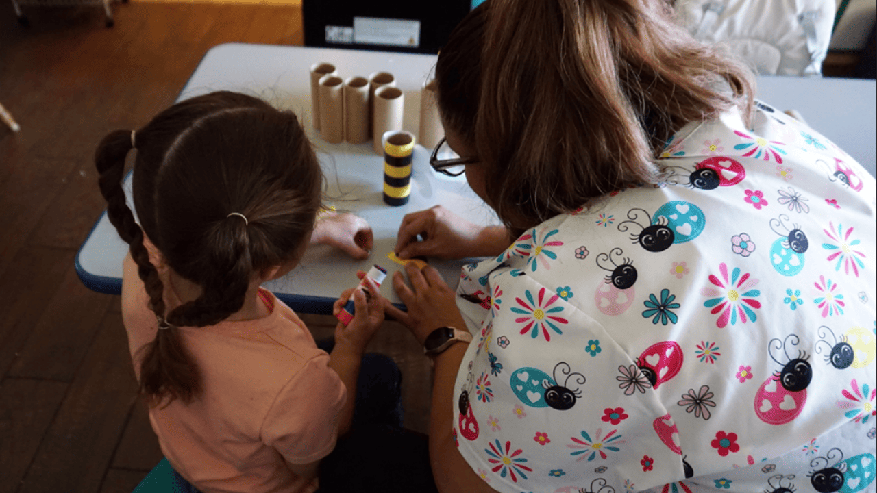 Maggi, a child care provider in New Mexico, with a preschooler in her care working on an art project.