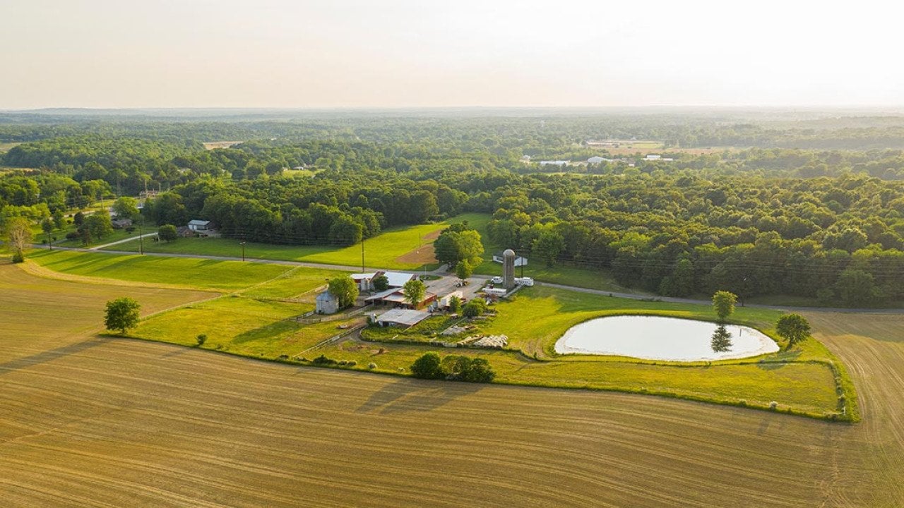 An aerial view of a small farm in southern Indiana during golden hour on a sunny summer day.