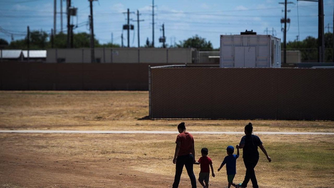 Immigrant woman and children walk across a field as U.S. Immigration and Customs Enforcement (ICE) and Enforcement and Removal Operations (ERO) hosts a media tour at the South Texas Family Residential Center, August 2019.